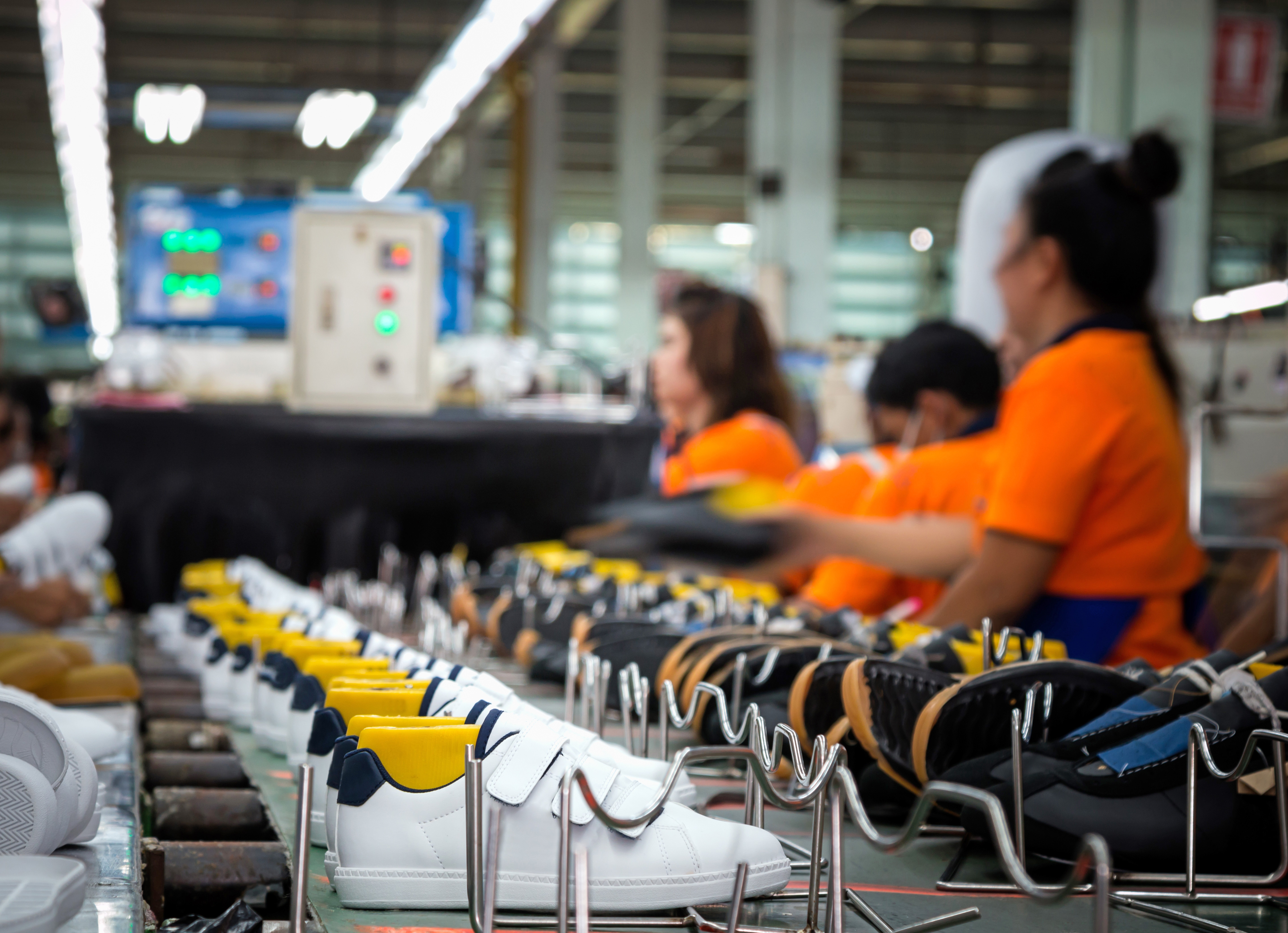 Workers making sport shoes in footwear production line
